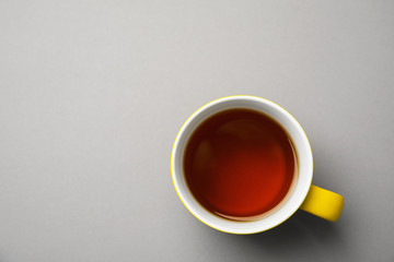 Cup of black tea on color background, top view