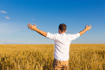 Young man stands in the middle of a wheat field and enjoys life. freedom