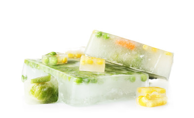 Fresh vegetables frozen in ice cubes on white background