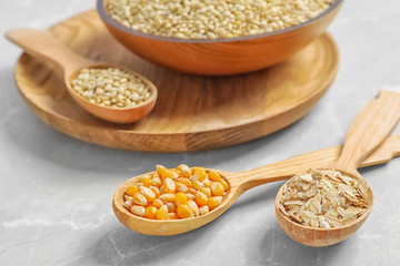 Spoons with different types of grains and cereals on table