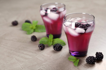 Fototapeta na wymiar Glasses with iced blackberry lemonade on grey table