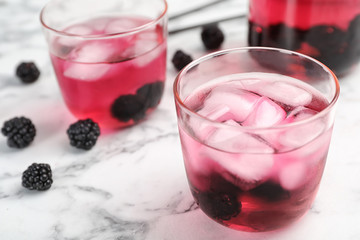 Glass with iced blackberry lemonade on marble table