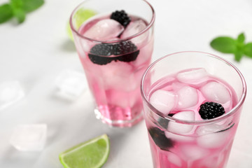 Glasses with iced blackberry lemonade on table, closeup
