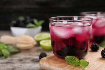 Glass with iced blackberry lemonade on table