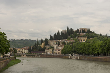 Fototapeta premium Castel San Pietro against a cloudy sky with Adige river in forefront