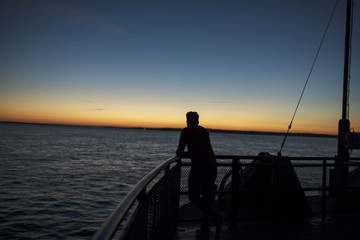 Fototapeta premium a guy looks from a boat railling a summer sunset