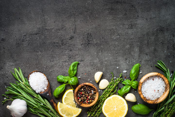 Selection of spices herbs and greens on black top view. 