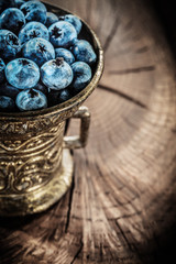 Ripe blueberries in vintage metal bowl on grunge board