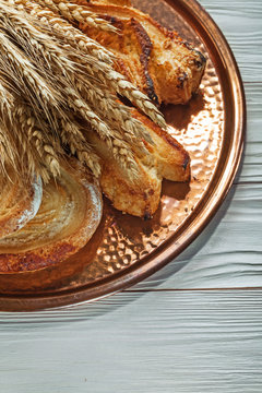 Rye ears baked pastry brass tray on wooden background