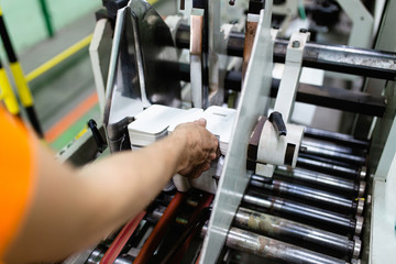 Close up shot of worker's hand preparing carton for printing in a modern printing house.