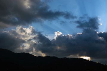 rays of the sun making their way through the clouds against the backdrop of the peaks of the mountains
