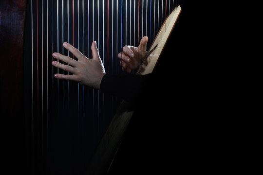 Harp player. Hands playing Irish harp strings