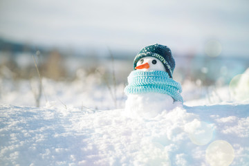 Little snowman in a cap and a scarf on snow in the winter. Christmas card with a lovely snowman,...