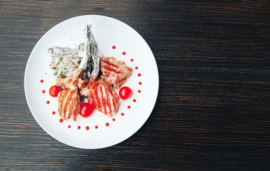 Grilled steak on a bone with tomatoes on a white plate. Hot Meat Dishes. top view