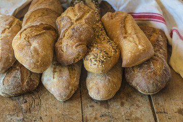 Various of french country breads and linen napkin on rustic wooden background with copy space