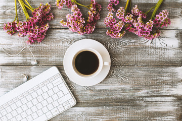 Top view of a keyboard, headphones and a cup of coffee and a purple flower on a gray wooden table. Flat design.