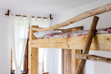 details of the interior of a bedroom of an old country house built with rough wood.