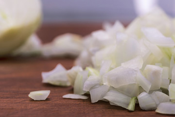 Cut into small pieces white onions on a wooden background, close-up.