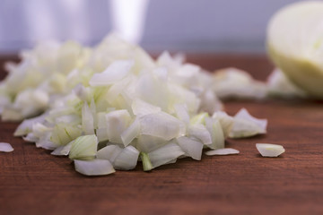 Pieces of finely chopped onions on a wooden background close-up.