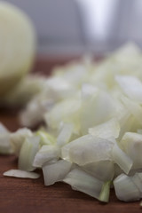 Chopped into small pieces white onion, close-up on a wooden background, vertical frame.