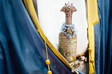 Traditional Omani Ceremonial Silver Dagger Hilt on Belt of Man Wearing Blue Robes with Yellow Trim