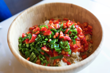 Quinoa salad with fresh vegetables in a bowl in the kitchen at home.