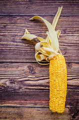 single curly drying corn cob on dark wooden background flat lay top view © dark_blade