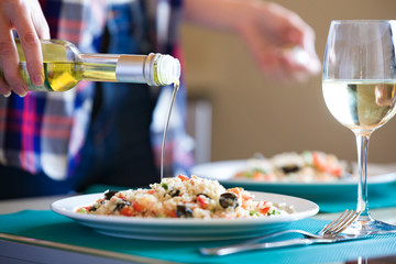 Young woman seasoning the quinoa salad in the home kitchen.