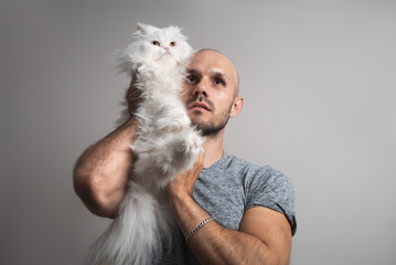 Bald brutal unshaven man holding a big white Persian cat