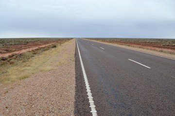 Fototapeta na wymiar Straight flat road through the desert in outback Australia stretching to the vanishing point