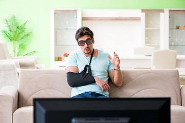 Arm injured man sitting on the sofa watching tv