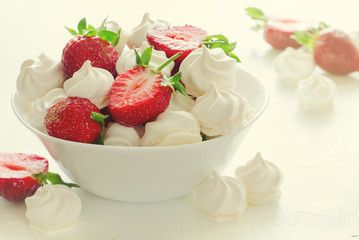 Fresh strawberries and meringues on white background
