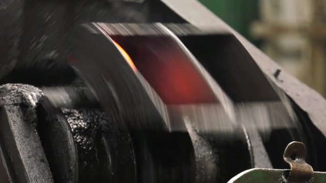 Production of steel screws in the factory ferrous metals. Hot red and orange nuts fall from the top to the container. Closeup
