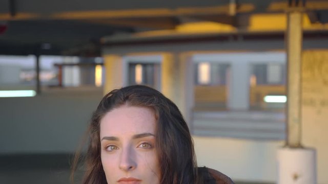 Young female dancer gets up and puts on her hood, looks into the camera and walks away