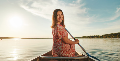Smiling young woman paddling her canoe on a sunny day
