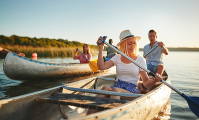 Smiling young woman canoeing with friends on a sunny afternoon