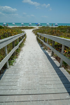 Dramatic vertical view of Wood Bridge looking toward a Sandy Ocean Beach with Colorful Umbrellas on a Sunny Day