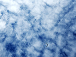 The plane is flying in the sky and the clouds are overcast.