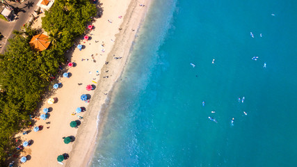 Aerial : people enjoying the summer at  beach line,waves breaking against the coastal line at Bali island,Indonesia