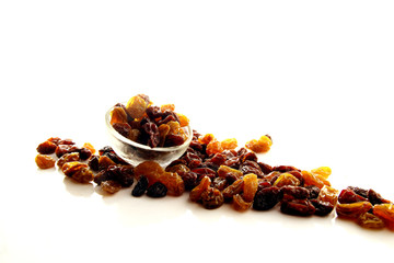 Raisins on white background / A raisin is a dried grape. Raisins are produced in many regions of the world and may be eaten raw or used in cooking, baking, and brewing