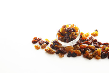 Raisins on white background / A raisin is a dried grape. Raisins are produced in many regions of the world and may be eaten raw or used in cooking, baking, and brewing