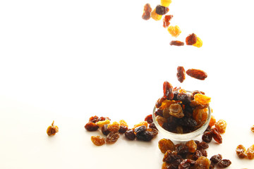 Raisins on white background / A raisin is a dried grape. Raisins are produced in many regions of the world and may be eaten raw or used in cooking, baking, and brewing