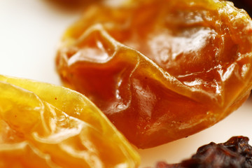 Close up raisin texture as background / A raisin is a dried grape. Raisins are produced in many regions of the world and may be eaten raw or used in cooking, baking, and brewing