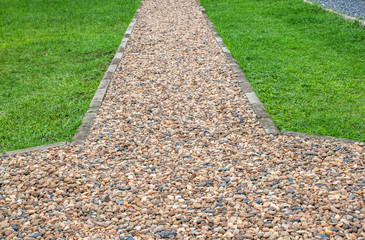 Walkway paved with gravel beside a green lawn.