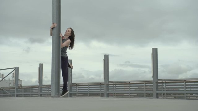 young girl dancing around a grey pier in an urban area
