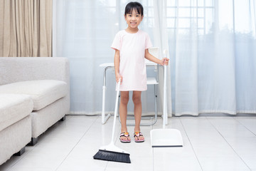 Fototapeta na wymiar Asian Chinese little girl helping doing cleaning with broom and dustpan