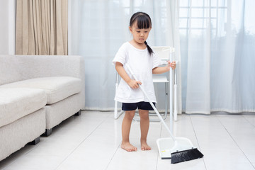 Fototapeta premium Asian Chinese little girl helping doing cleaning with broom and dustpan
