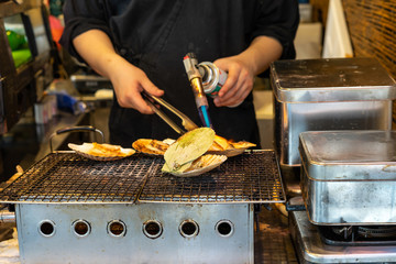Chef using flame torch burn on Japanese scallop and Japanese shellfish