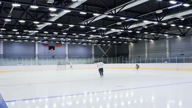 young hockey player with stick skates along ice arena