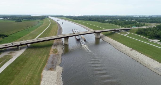 A long tow is running under a highway bridge on the Chain of Rocks Canal above St Louis, aerial view